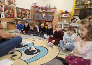 Dzieci siedzą w kole i rozpoznają zapachy świąteczne.