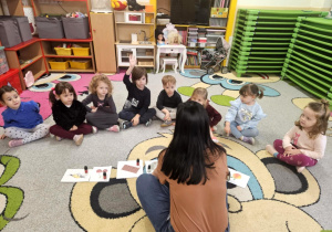 Dzieci siedzą w kole i rozpoznają zapachy świąteczne.