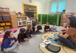 Dzieci siedzą w kole i rozpoznają zapachy świąteczne.