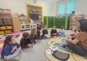 Dzieci siedzą w kole i rozpoznają zapachy świąteczne.