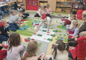 Dzieci siedzą na dywanie podczas zajęć otwartych.