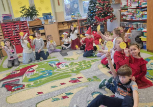 Dzieci siedzą na dywanie podczas zajęć otwartych.