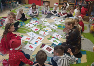 Dzieci siedzą na dywanie podczas zajęć otwartych.