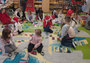 Dzieci siedzą na dywanie podczas zajęć otwartych.