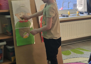 Dziecko wrzuca babeczkę do makiety babci lub dziadka.