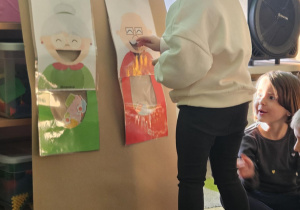 Dziecko wrzuca babeczkę do makiety babci lub dziadka.