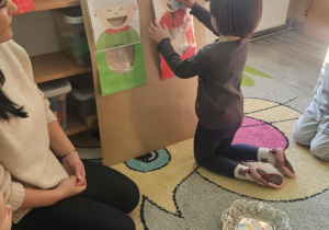 Dziecko wrzuca babeczkę do makiety babci lub dziadka.