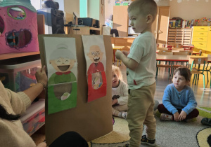 Dziecko wrzuca babeczkę do makiety babci lub dziadka.