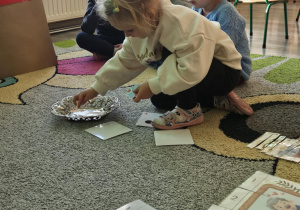 Dziecko wrzuca babeczkę do makiety babci lub dziadka.