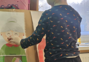 Dziecko wrzuca babeczkę do makiety babci lub dziadka.