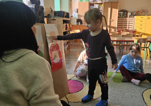 Dziecko wrzuca babeczkę do makiety babci lub dziadka.