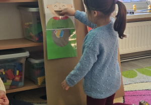 Dziecko wrzuca babeczkę do makiety babci lub dziadka.