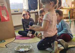 Dziecko wrzuca babeczkę do makiety babci lub dziadka.