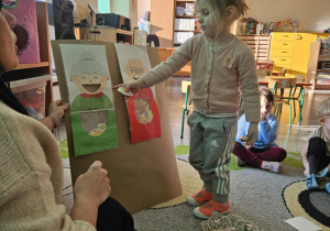 Dziecko wrzuca babeczkę do makiety babci lub dziadka.