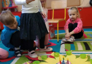 Dziecko układa koraliki na słoneczku urodzinowym.