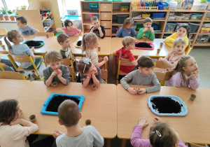 Dzieci sadzą cebulki w doniczkach.