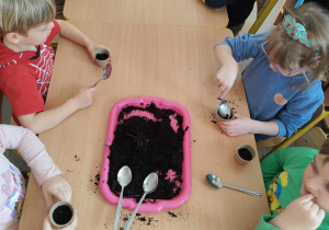 Dzieci sadzą cebulki w doniczkach.