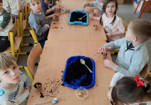 Dzieci sadzą cebulki w doniczkach.