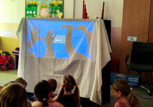Dzieci oglądają przedszkolny teatr cieni.