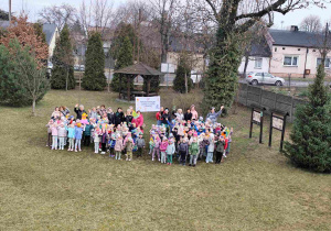 Dzieci świętują nadejście wiosny koło przedszkola.