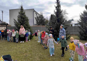 Dzieci świętują nadejście wiosny koło przedszkola.