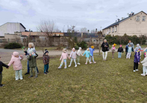 Dzieci świętują nadejście wiosny koło przedszkola.