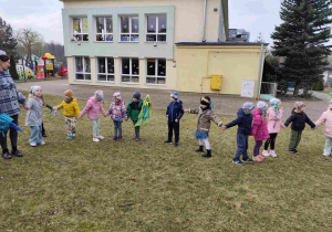 Dzieci świętują nadejście wiosny koło przedszkola.