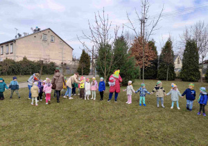 Dzieci świętują nadejście wiosny koło przedszkola.