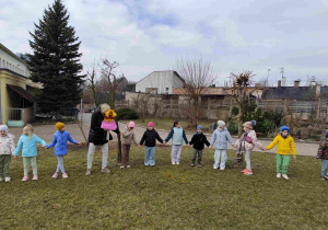 Dzieci świętują nadejście wiosny koło przedszkola.