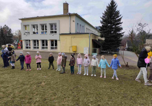 Dzieci świętują nadejście wiosny koło przedszkola.
