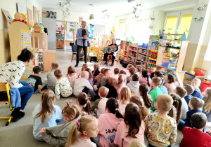 Dzieci słuchają gitarowego koncertu.