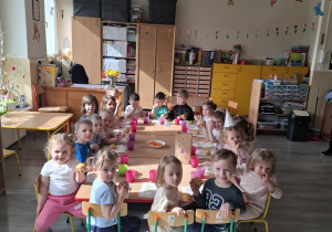 Dzieci przy stolikach podczas poczęstunku urodzinowego.