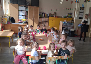 Dzieci przy stolikach podczas poczęstunku urodzinowego.