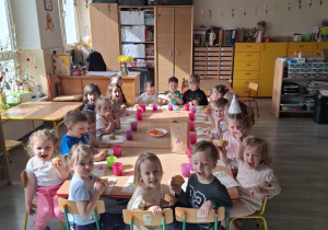 Dzieci przy stolikach podczas poczęstunku urodzinowego.
