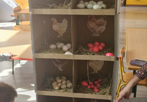 Dzieci przeliczają jajka w kurniku.