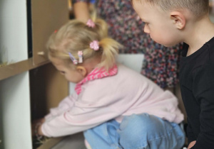 Dzieci przeliczają jajka w kurniku.