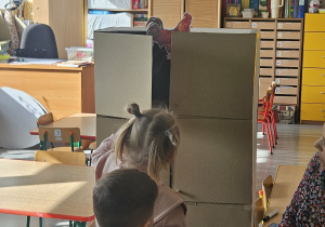 Dzieci przeliczają jajka w kurniku.