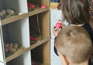 Dzieci przeliczają jajka w kurniku.