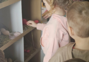 Dzieci przeliczają jajka w kurniku.