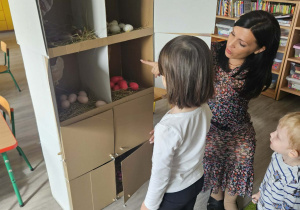 Dzieci przeliczają jajka w kurniku.