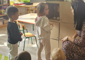 Dzieci przeliczają jajka w kurniku.