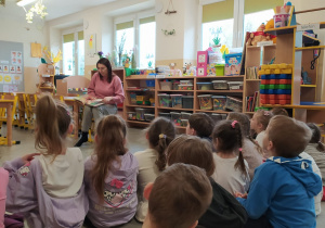 Mama Oli czyta dzieciom książkę.