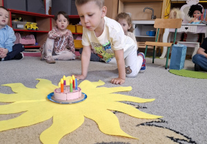 Jubilat zdmuchuje świeczkę na torcie.