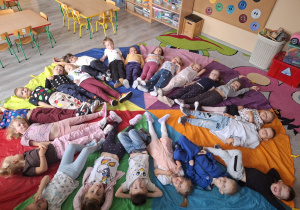 Dzieci ubrane w kropeczki leżą na chuście animacyjnej.