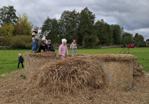 Dzieci wchodzą na snopki siana.