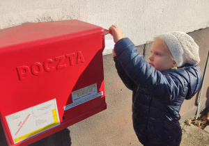 Chłopiec wrzuca list do skrzynki.