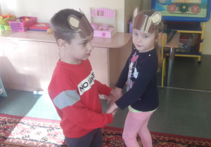 Chołpiec i dziewczynka tańczą z opaskami na głowach.
