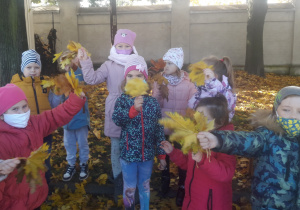 Dzieci trzymają w rączkach liście.