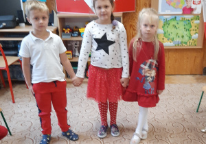Dwie dziewczynki i chłopiec ubrani na biało-czerwono.