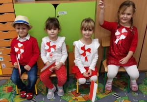 Dzieci siedzą z flagą w rączkach.
